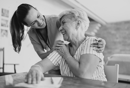 A caregiver embraces her aging loved one.
