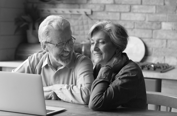 Man and woman smiling in front of a laptop computer