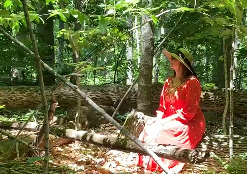 A woman meditates in the woods. 