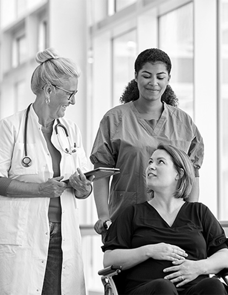 A doctor and nurse smile and talk to a female patient