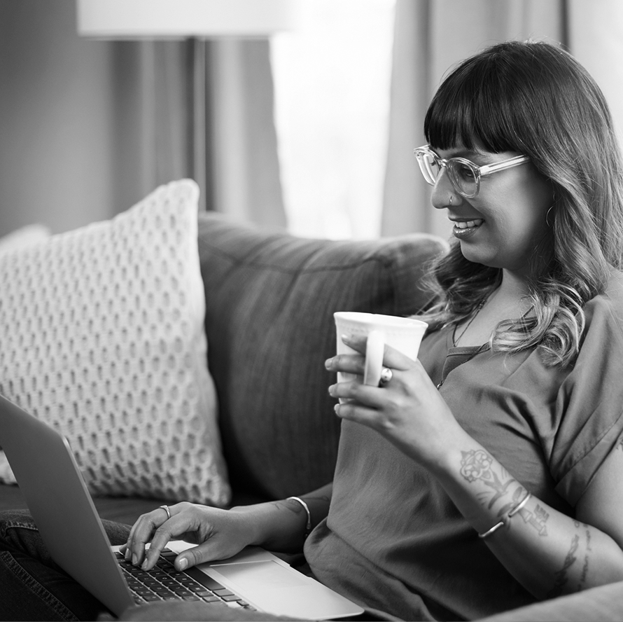 A woman sitting on a couch with her laptop and coffee