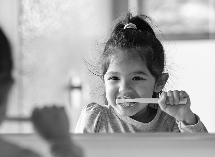 A young girl brushes her teeth.