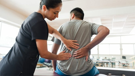 A doctor examines a patient's back.