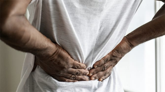 A person grabs the lower part of their back.