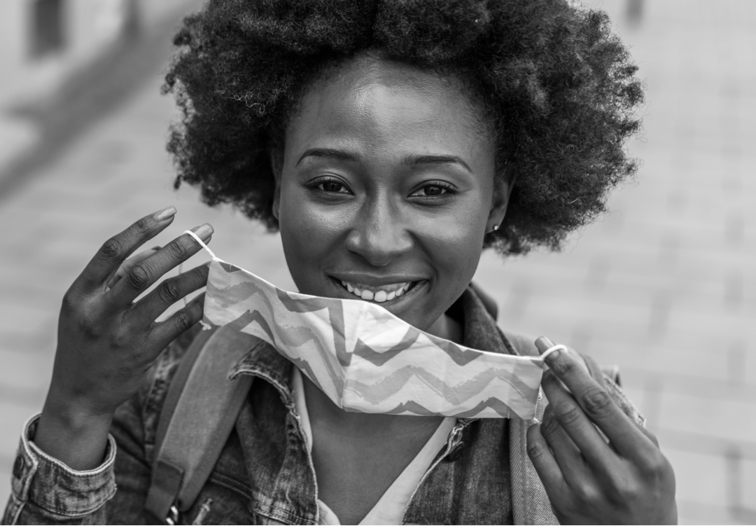 A woman smiles as she takes off her mask