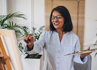 An older woman painting at an easel