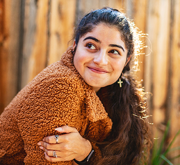 A smiling young woman in a fuzzy sweater