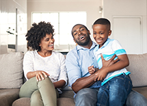 A mother and father sit on the couch with their son.