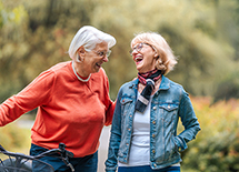 Two senior women laugh together while on a walk.