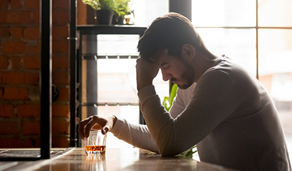 A man resting his head in his hand while sitting at a bar