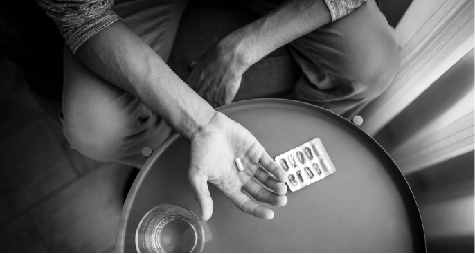 Photo of a man looking at pills in his hand