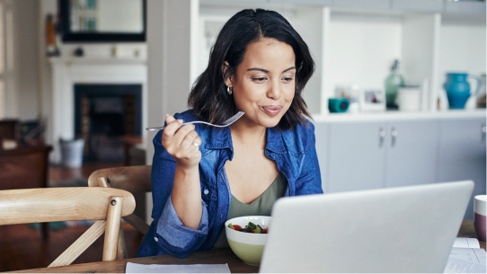 A woman eats at her computer