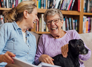An older woman and her caregiver smiling at one another