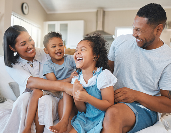 A smiling family with a mother, father, son and daughter sitting together on a couch