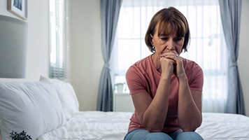 A woman sitting on the edge of her bed