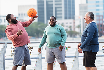three men playing basketball in a park by the water