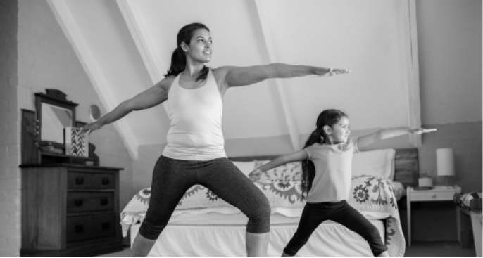 A mother and daughter practice yoga together