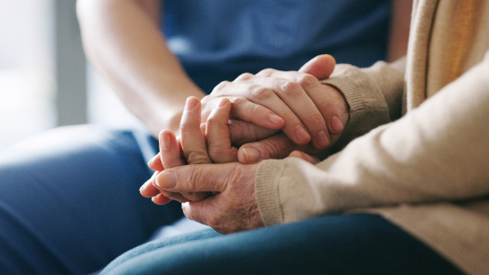 Two seniors hold hands and discuss mental health