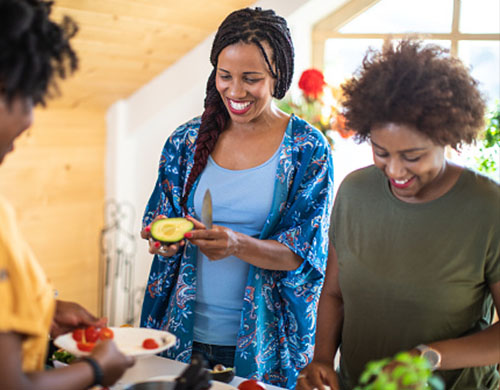 Three smiling women preparing food together