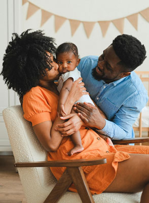 A mother and father kissing their baby