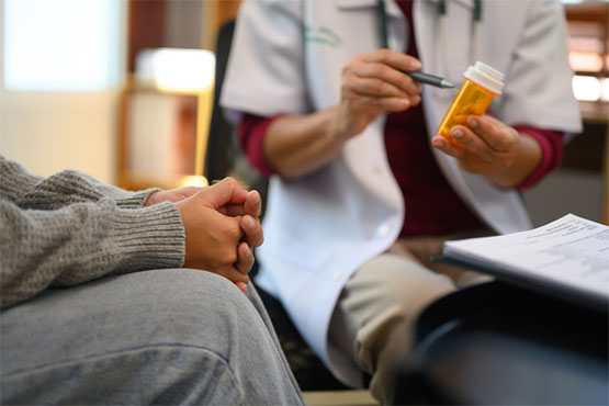 A doctor shows a prescription medicine bottle to their patient