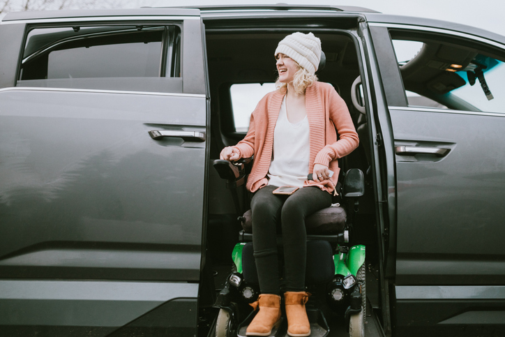 woman sitting in wheelchair as it's lowered from a vehicle