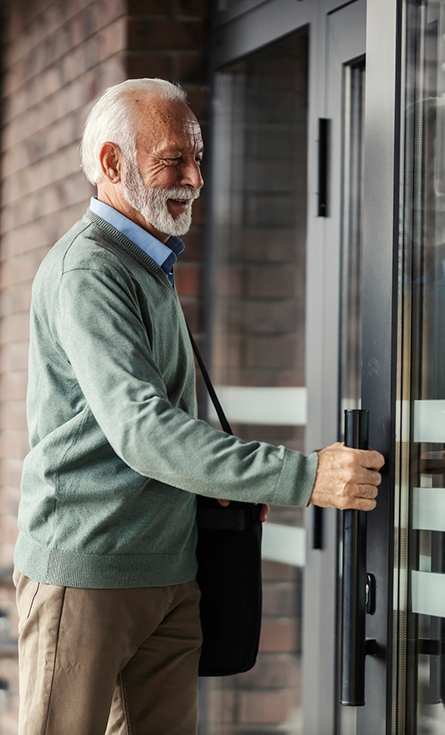 A senior man opening a door to a medical facility