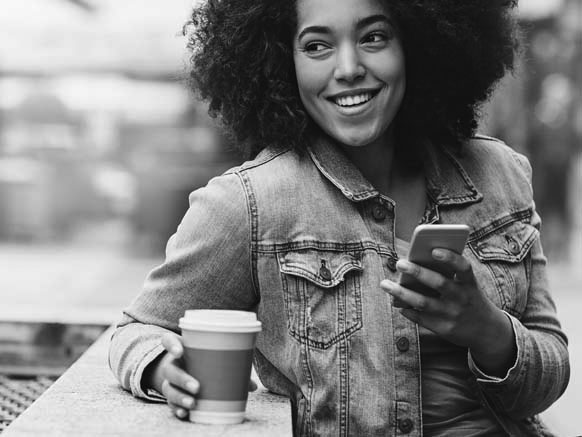  Young woman holding cell phone and generic to-go coffee cup