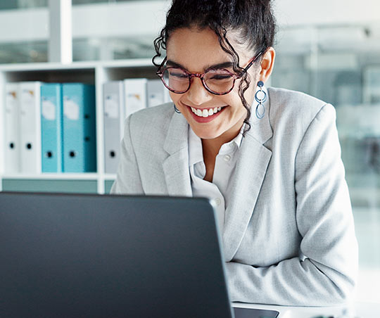 A smiling woman works at a laptop