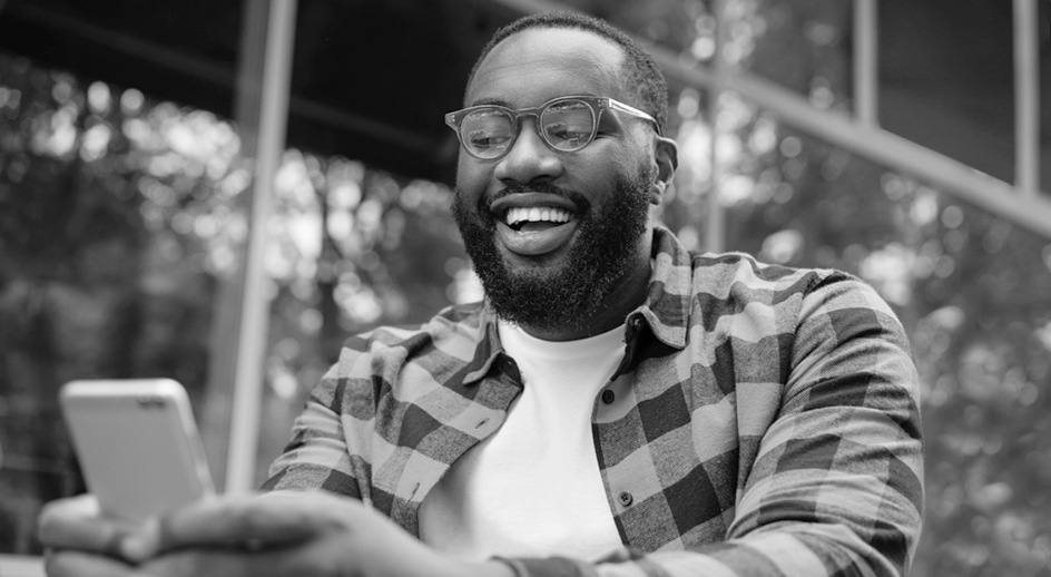 A man smiles while looking at his mobile device