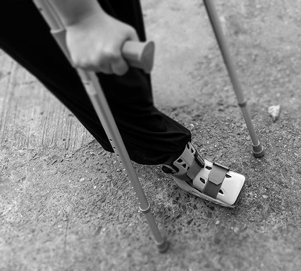 A person using a walking boot and crutches