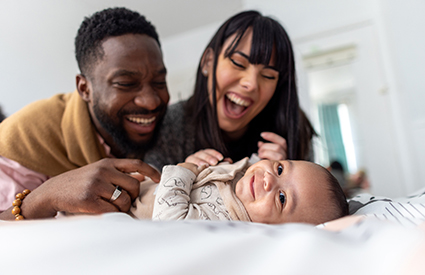 A couple smiles and holds their newborn.