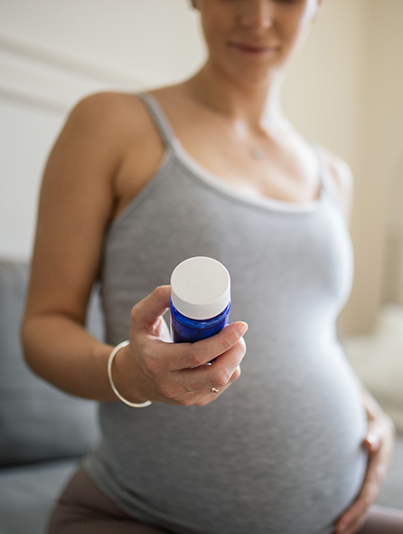 A woman holds her vitamins in her hands.