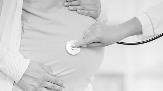 A doctor listens to a mother's pregnant belly