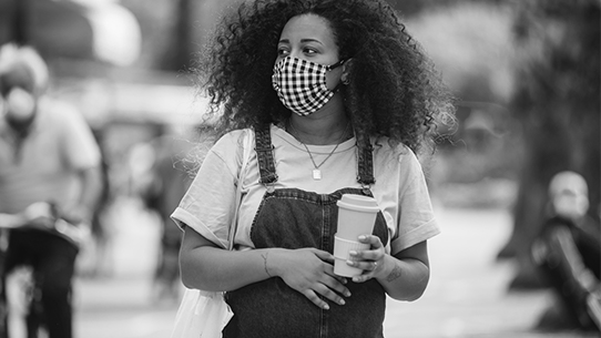 A woman with a mask holds a cup