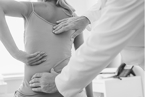 A doctor touchs a woman's spine.