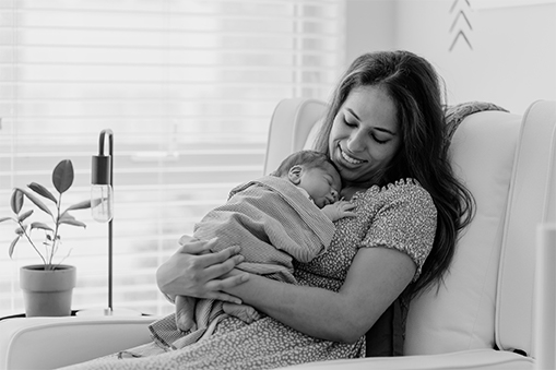 A woman smiles while holding her newborn.