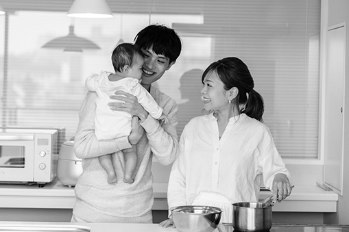 A couple smiles and holds their newborn.