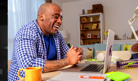 A man smiling at a laptop on a Zoom call