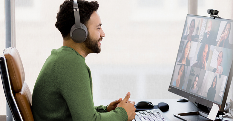 A man sits in front of his computer while wearing headphones during a virtual meeting.