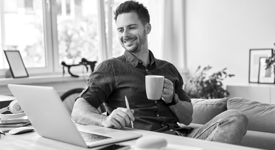 Man with a cup of coffee looking at a laptop