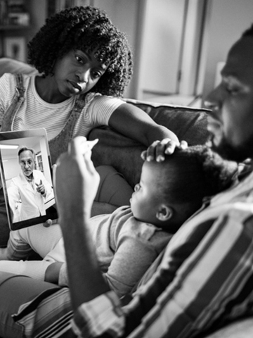 A mom and dad sit with their young child during a virtual appointment