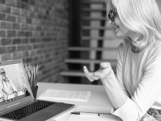 A woman sitting in front of a laptop on a virtual call