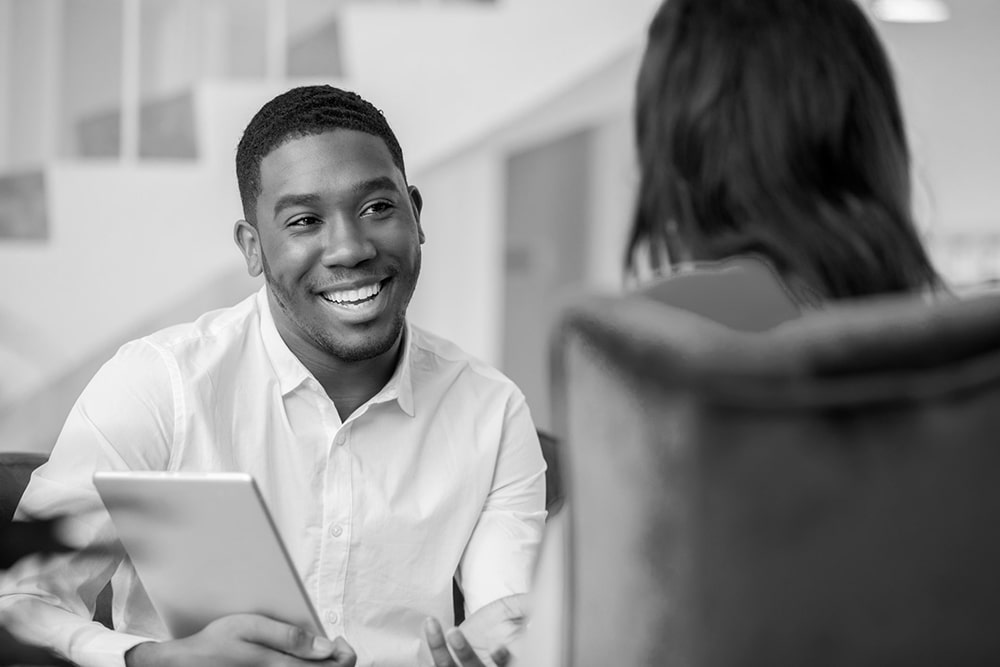 A man smiles while helping someone with their mental health. 