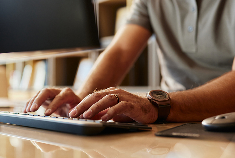 A close-up of a man's hands typing on a computer keyboard.