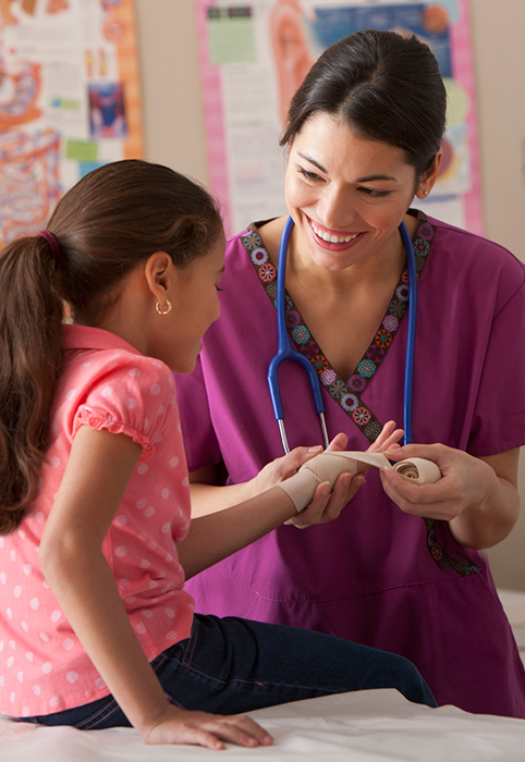 A medical professional wraps a young girl's wrist with an elastic bandage.