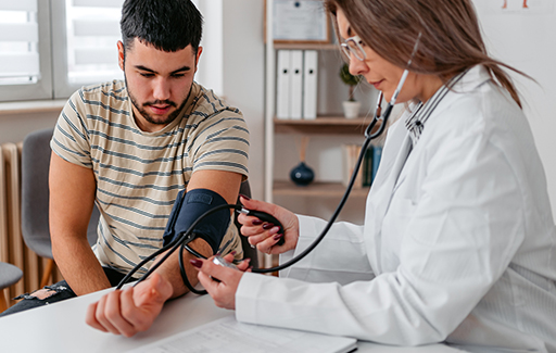 A medical professional checks a young man's blood pressure.