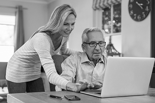 A young woman teaches an older man how to navigate through his health care online