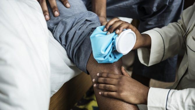 A doctor ices a patient's knee 