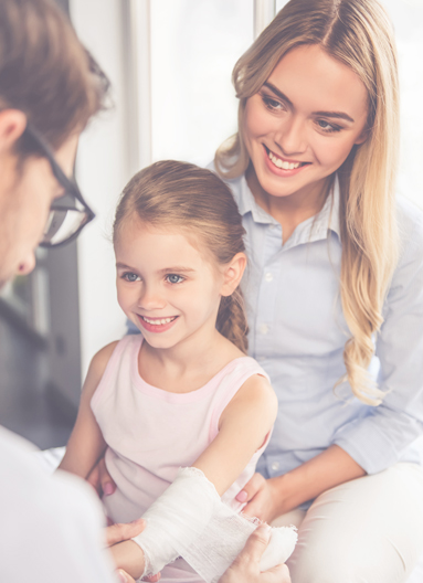 A doctor wraps a young girl's arm with a bandage while her mother holds her.